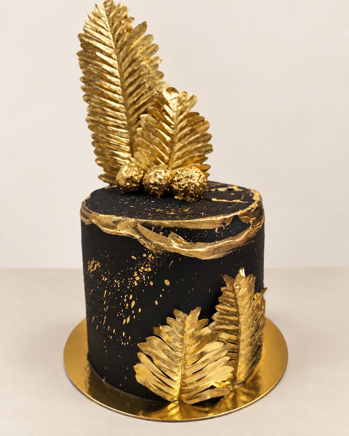 Torta negra con relieve y hojas decorativas doradas.