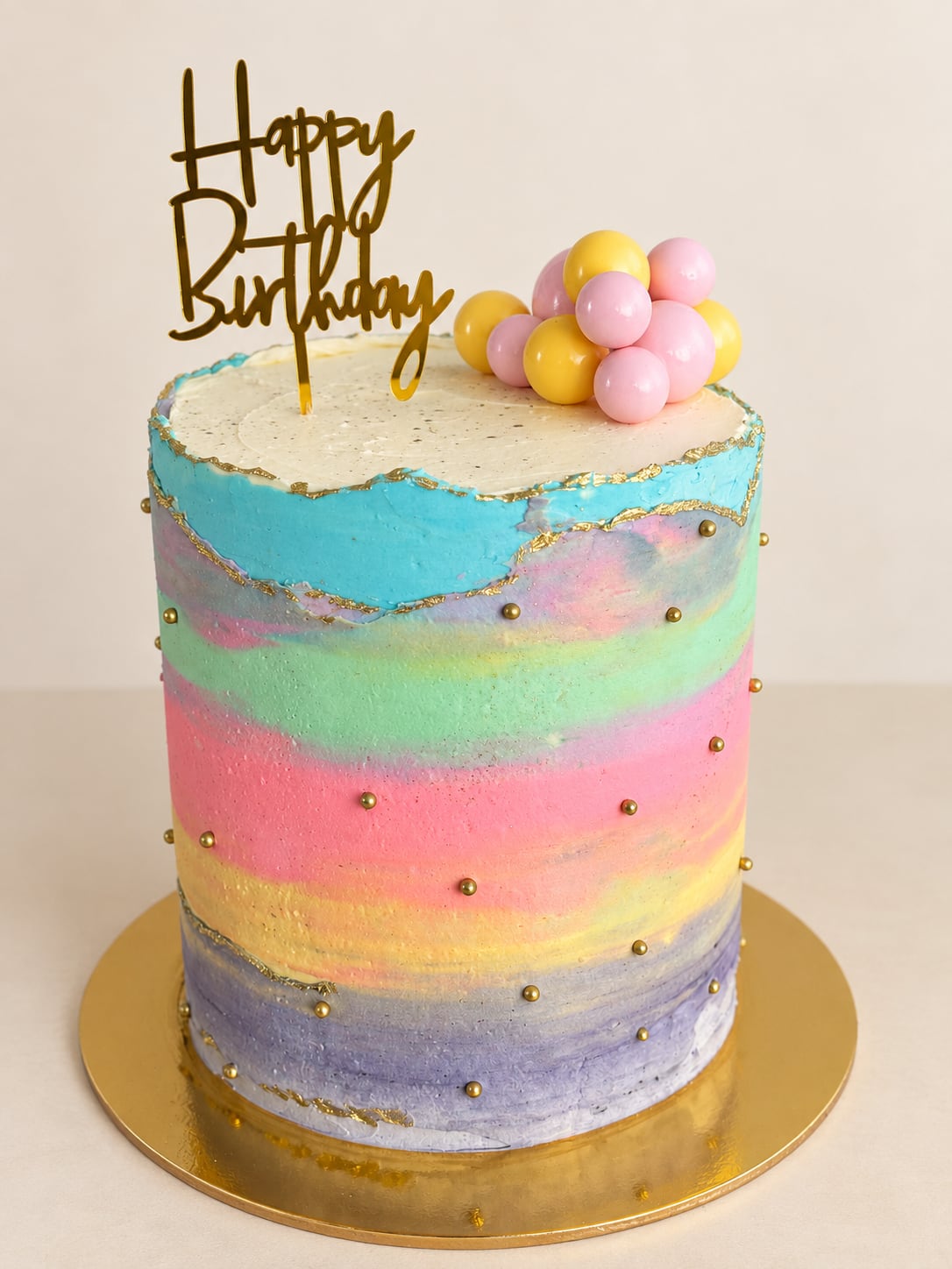 Torta alta con bandas de colores pastel, bordes dorados y esferas.