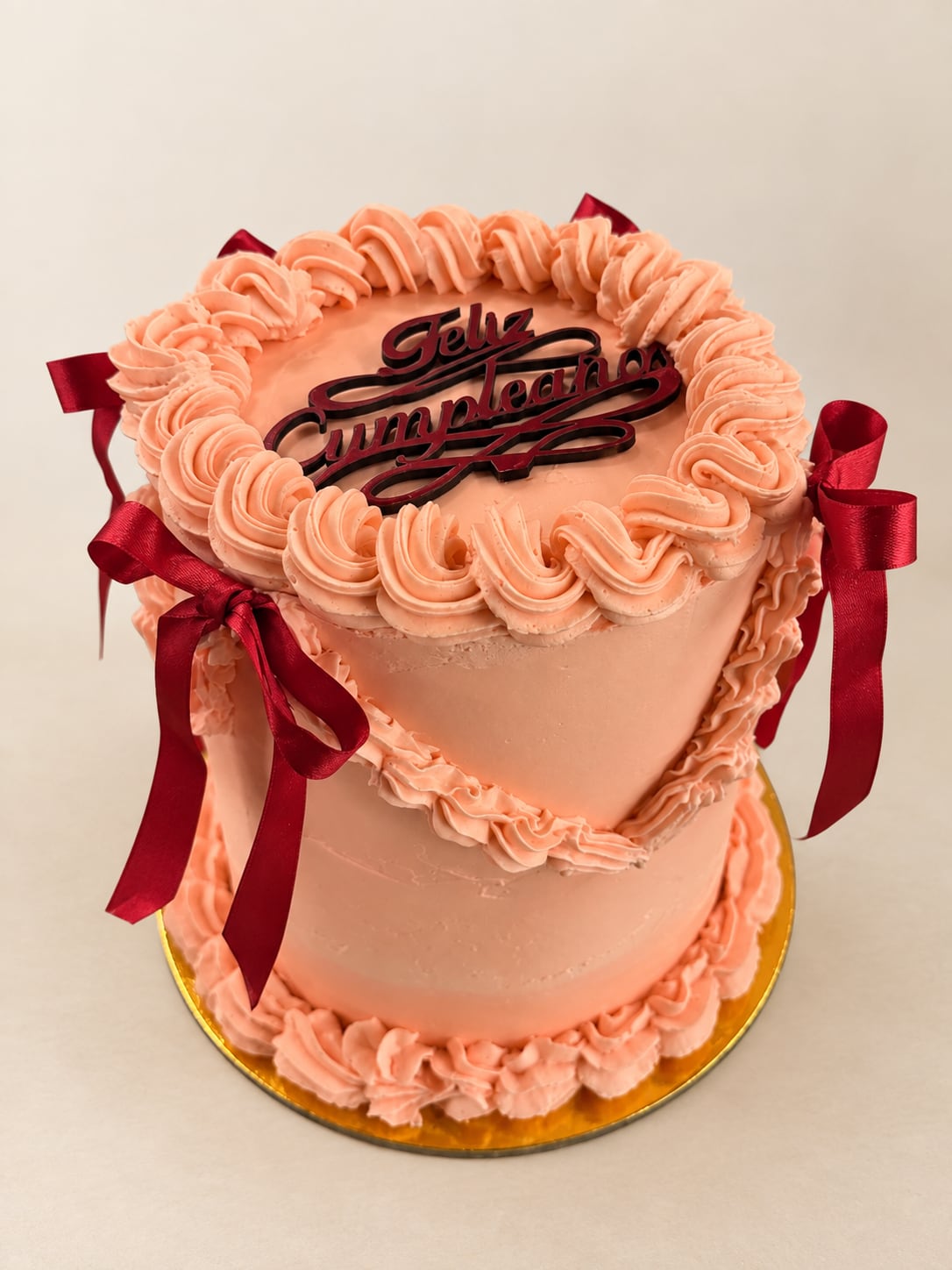 Torta rosa con ondas de manga y lazos burdeos.